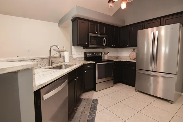 a kitchen with a sink stainless steel appliances and refrigerator