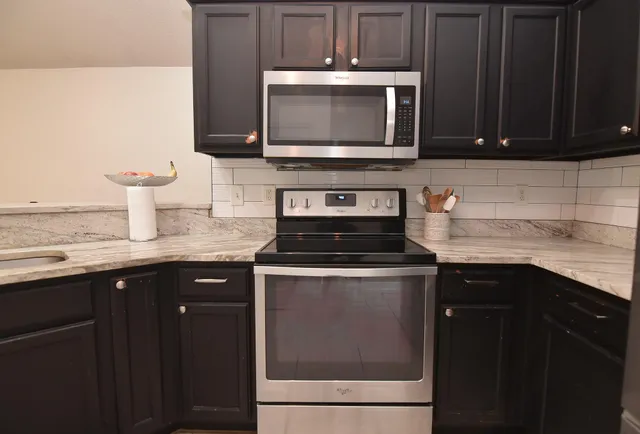 a kitchen with stainless steel appliances granite countertop a stove microwave and sink