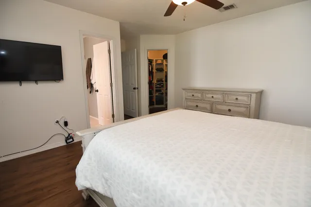 a bedroom with a bed and a flat tv screen on wall