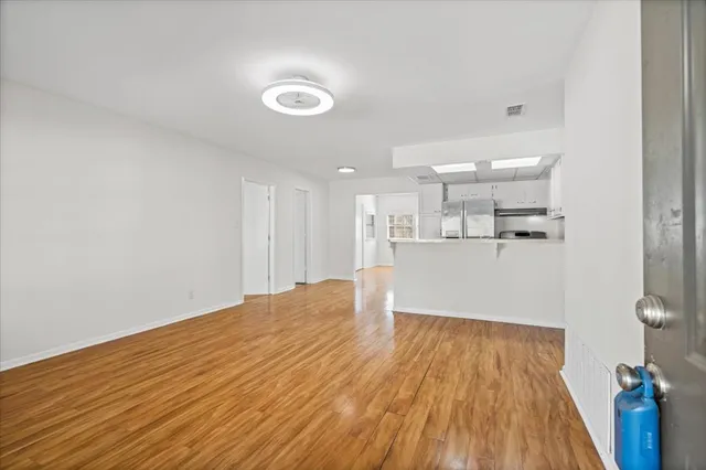 a big room with wooden floor and kitchen view