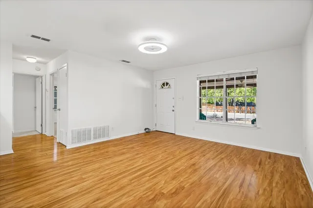 a view of an empty room with wooden floor and a window
