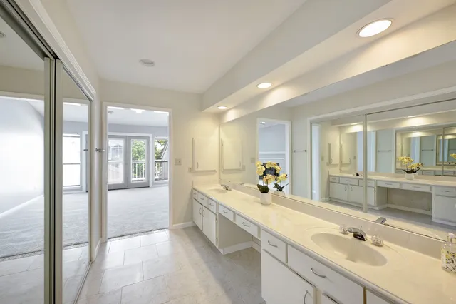 a spacious bathroom with a double vanity sink mirror and bathtub