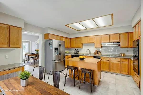 a kitchen with stainless steel appliances granite countertop a refrigerator a stove a sink a dining table and chairs with wooden floor