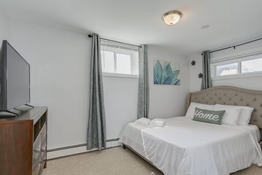134 Newbury Avenue, Unit 1A Quincy, MA 02171 - Photo 11 of 13 a bedroom with a bed and a flat tv screen on a dresser
