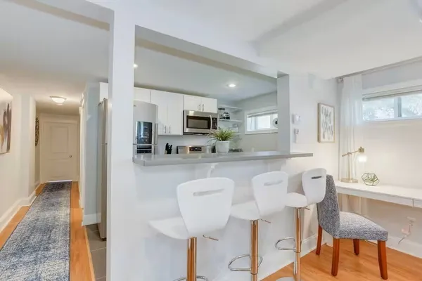 a kitchen with stainless steel appliances granite countertop a dining table chairs and a refrigerator