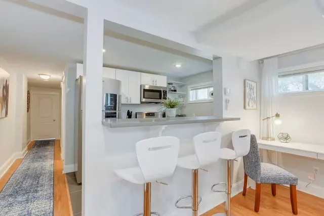 a kitchen with stainless steel appliances granite countertop a dining table chairs and a refrigerator