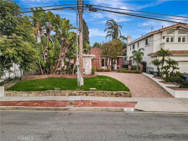 a front view of a house with a yard and potted plants