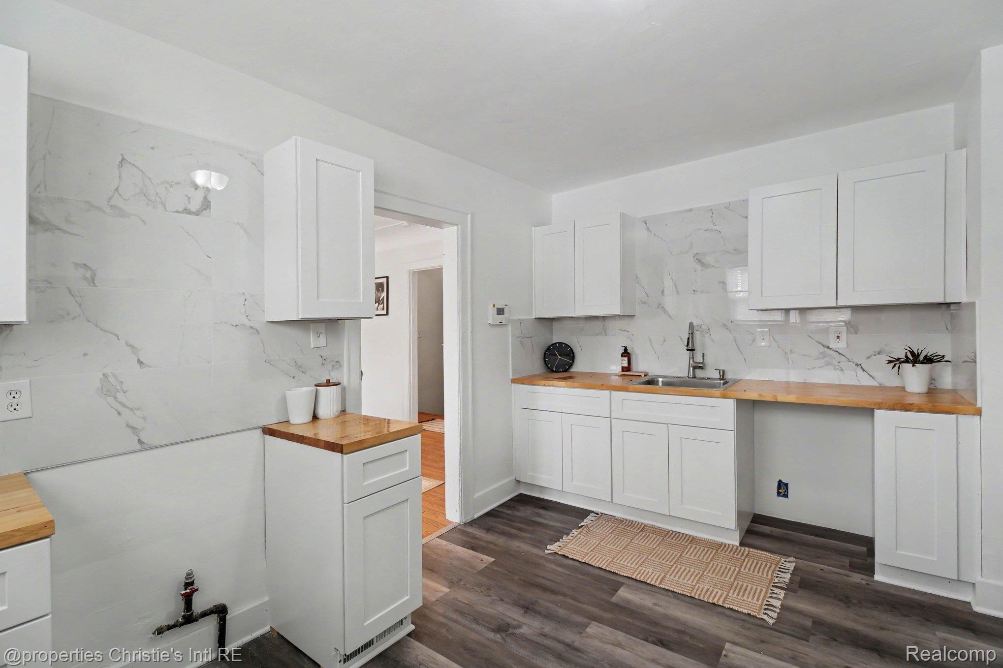 18315 Prairie Street Detroit, MI 48221 - Photo 6 of 16 Modern kitchen featuring white shaker cabinetry, wood-finish countertops, full-height decorative backsplash, and wood-finish flooring