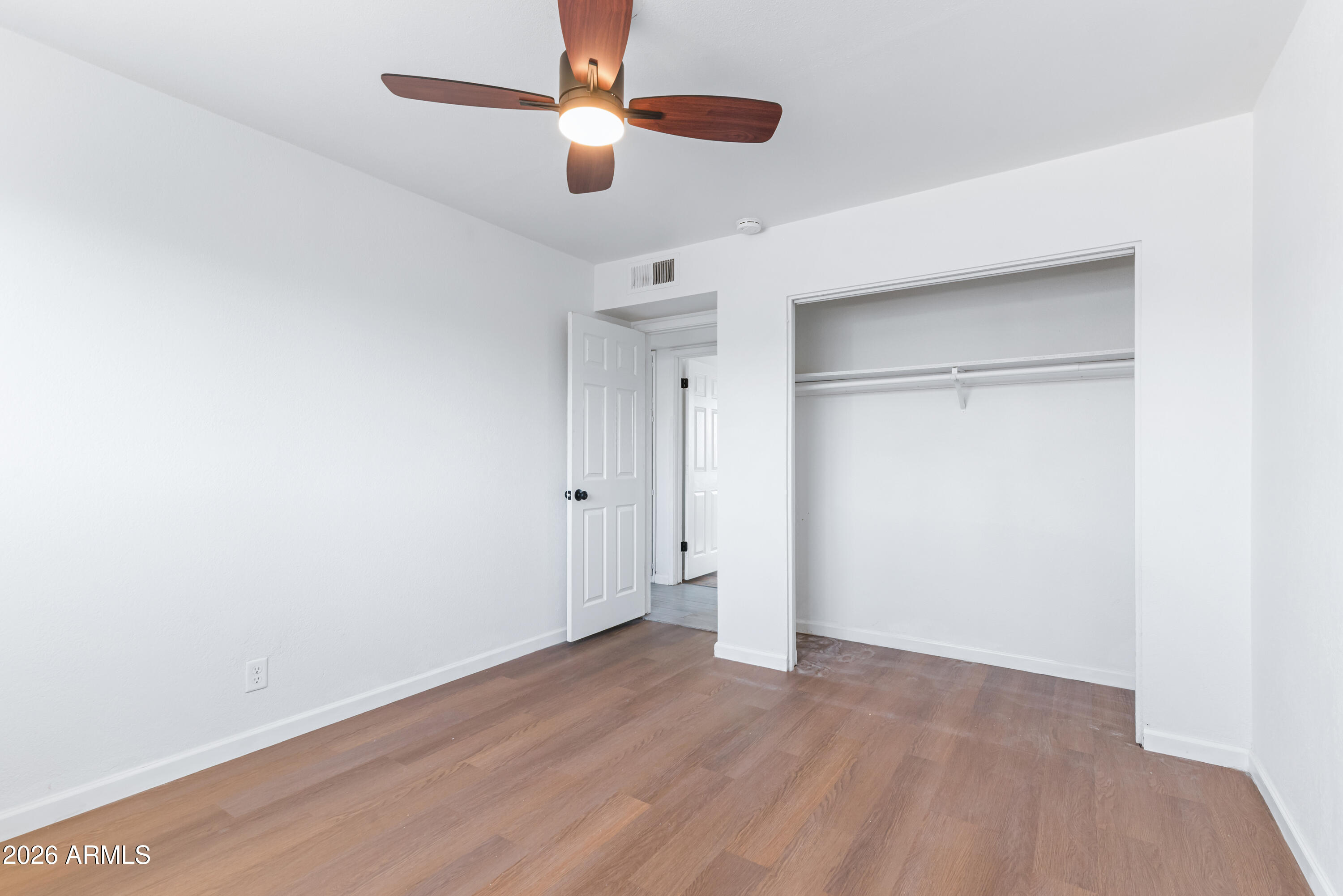 860 West McLellan Road Mesa, AZ 85201 - Photo 20 of 26 an empty room with wooden floor a ceiling fan and closet