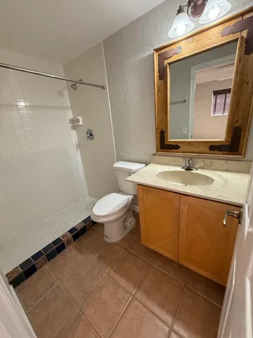 a bathroom with a granite countertop sink toilet and mirror