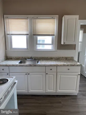 a kitchen with granite countertop white cabinets and a stove