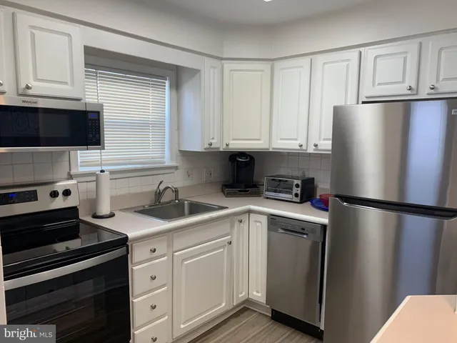 a kitchen with cabinets stainless steel appliances and a window