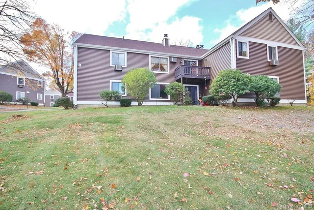 a view of a brick house with a big yard and large trees