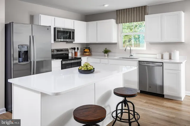 a kitchen with a refrigerator a stove a sink and white cabinets with wooden floor