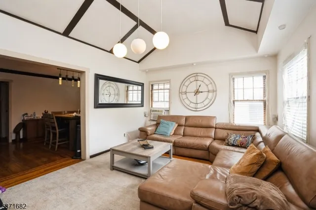a living room with furniture a clock on wall and a window