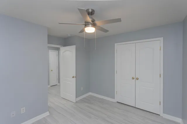 a view of an empty room with window and a ceiling fan