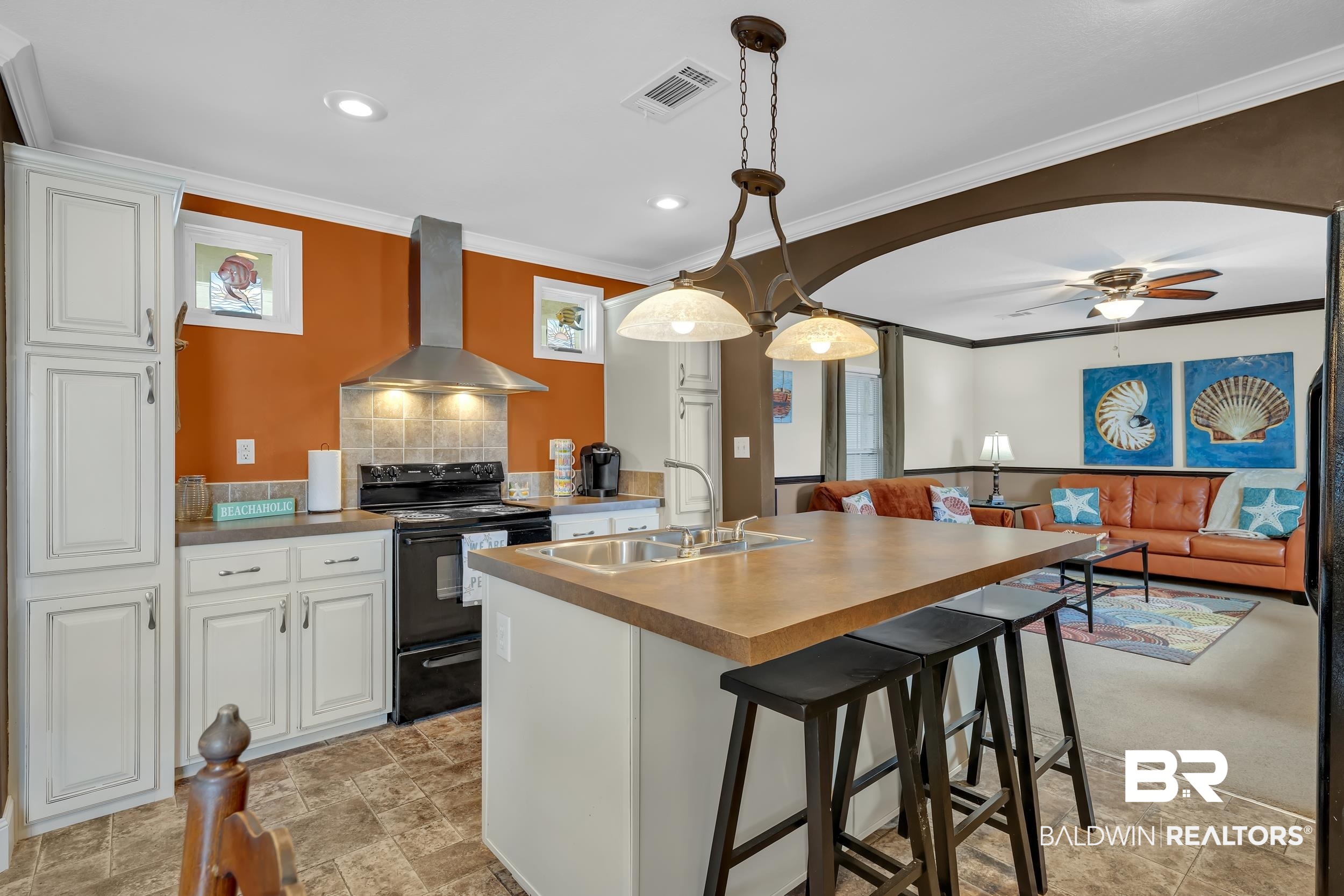 16707 Fort Morgan Road, Unit 8 Gulf Shores, AL 36542 - Photo 3 of 27 Kitchen featuring decorative backsplash, black electric range, a breakfast bar, wall chimney range hood, and white cabinets