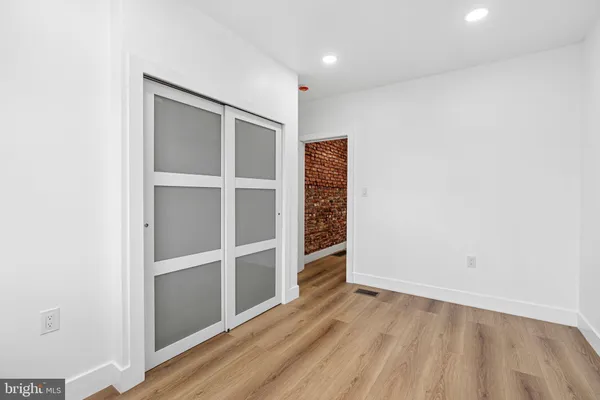 a view of an empty room with wooden floor and closet