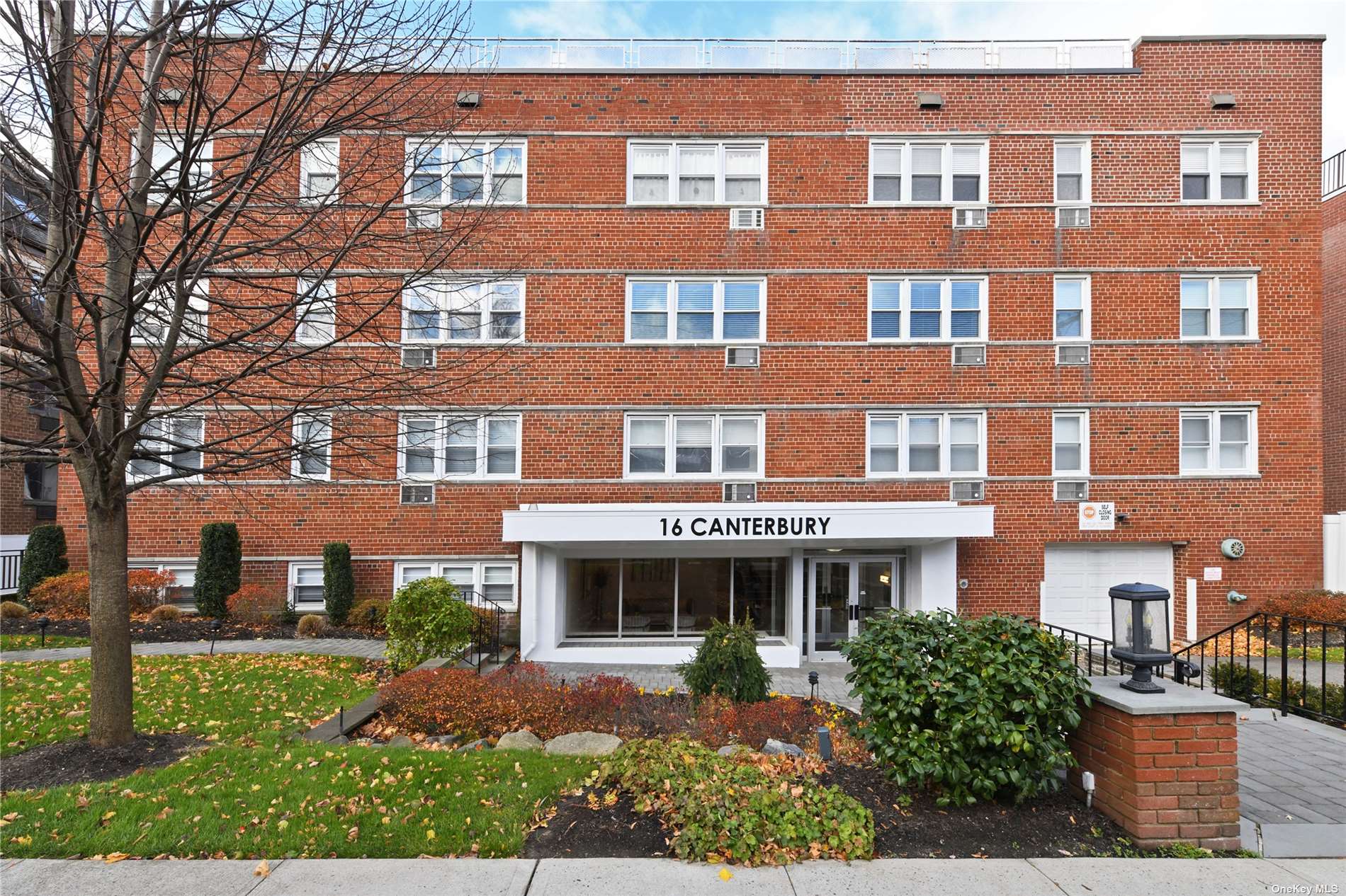 a front view of a building with garden and parking