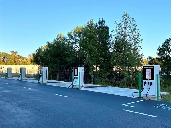 a kitchen with stainless steel appliances kitchen island granite countertop a refrigerator a sink a dining table and chairs with wooden floor