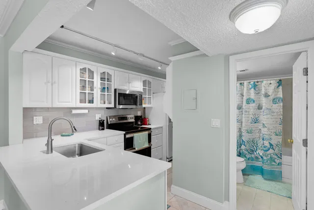 a kitchen with stainless steel appliances a sink a stove a refrigerator cabinets and a window