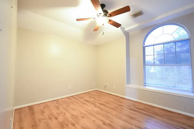 an empty room with a window and wooden floor