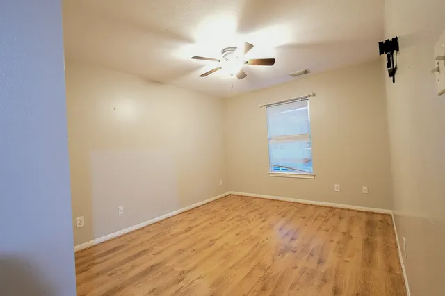 an empty room with a window and ceiling fan