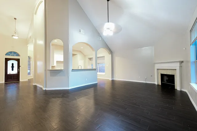 an empty room with wooden floor fireplace and windows