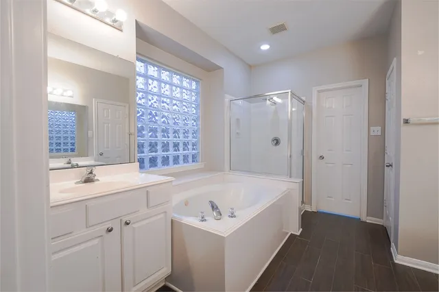 a bathroom with a bathtub a sink a vanity a window and a shower