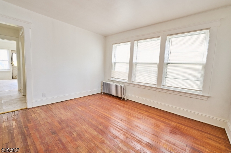 175 Madison Avenue, Unit 1 Elizabeth, NJ 07201 - Photo 3 of 10 an empty room with wooden floor and windows