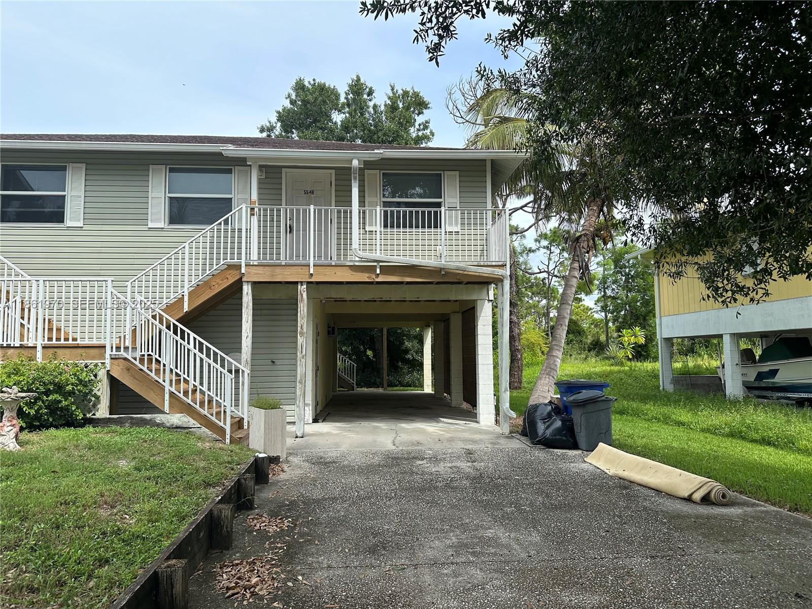 5548 Birdsong Lane, Unit 1 Bokeelia, FL 33922 - Photo 3 of 24 a front view of a house with a yard and garage