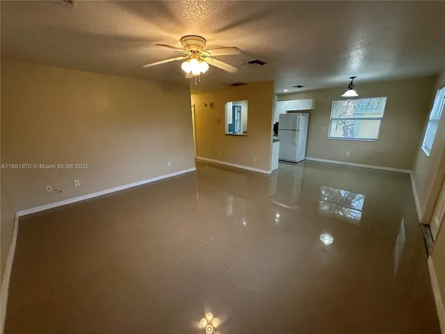 en empty room with windows and ceiling fan