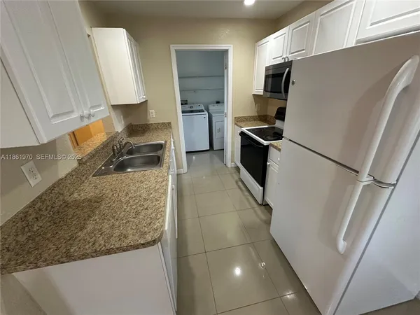 a kitchen with granite countertop a refrigerator and a sink