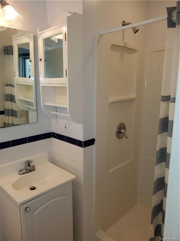 215 Harriman Road Irvington, NY 10533 - Photo 15 of 20 Bathroom with vanity, a shower with curtain, and tile walls