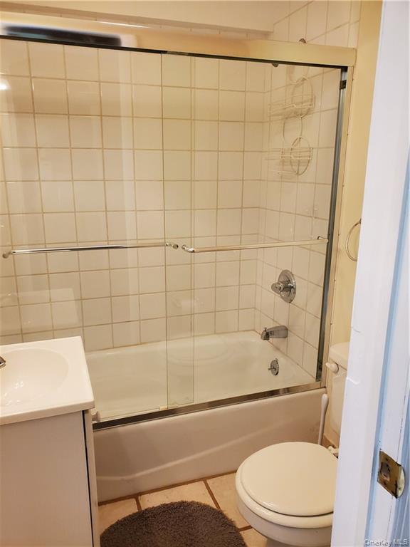 215 Harriman Road Irvington, NY 10533 - Photo 18 of 20 Bathroom featuring toilet, tile patterned floors, combined bath / shower with glass door, and vanity