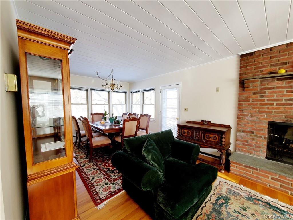 215 Harriman Road Irvington, NY 10533 - Photo 5 of 20 Living room featuring crown molding, light wood-style flooring, a brick fireplace, and a notable chandelier