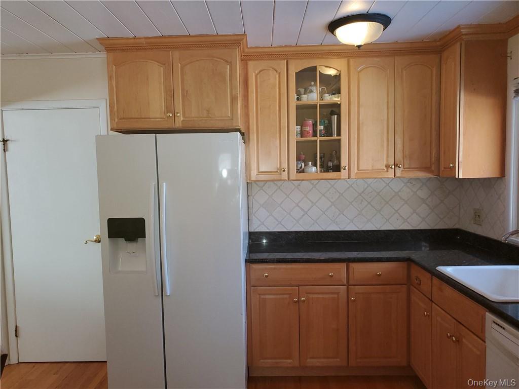 215 Harriman Road Irvington, NY 10533 - Photo 6 of 20 Kitchen featuring dark countertops, white appliances, glass insert cabinets, a sink, and backsplash