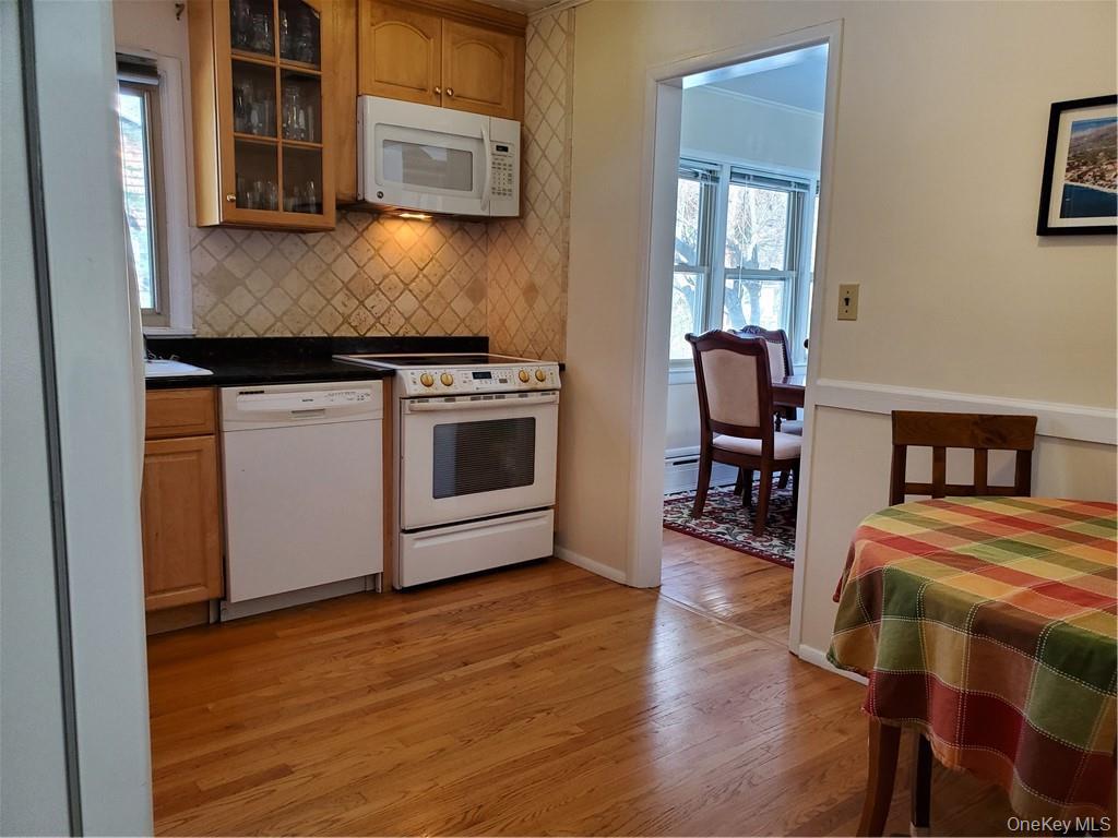 215 Harriman Road Irvington, NY 10533 - Photo 7 of 20 Kitchen featuring decorative backsplash, light wood-style flooring, white appliances, and glass insert cabinets