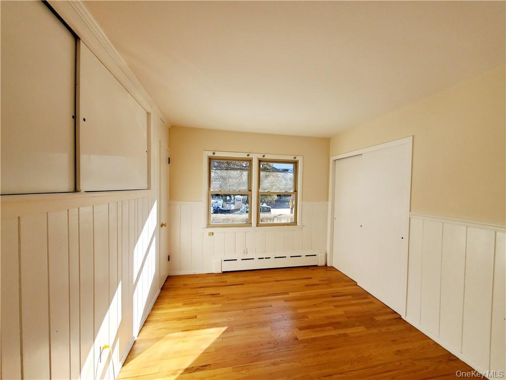 215 Harriman Road Irvington, NY 10533 - Photo 10 of 20 Empty room featuring light wood-style floors, a wainscoted wall, and a baseboard radiator
