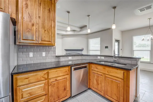 a kitchen with stainless steel appliances granite countertop a sink a stove and a wooden floors