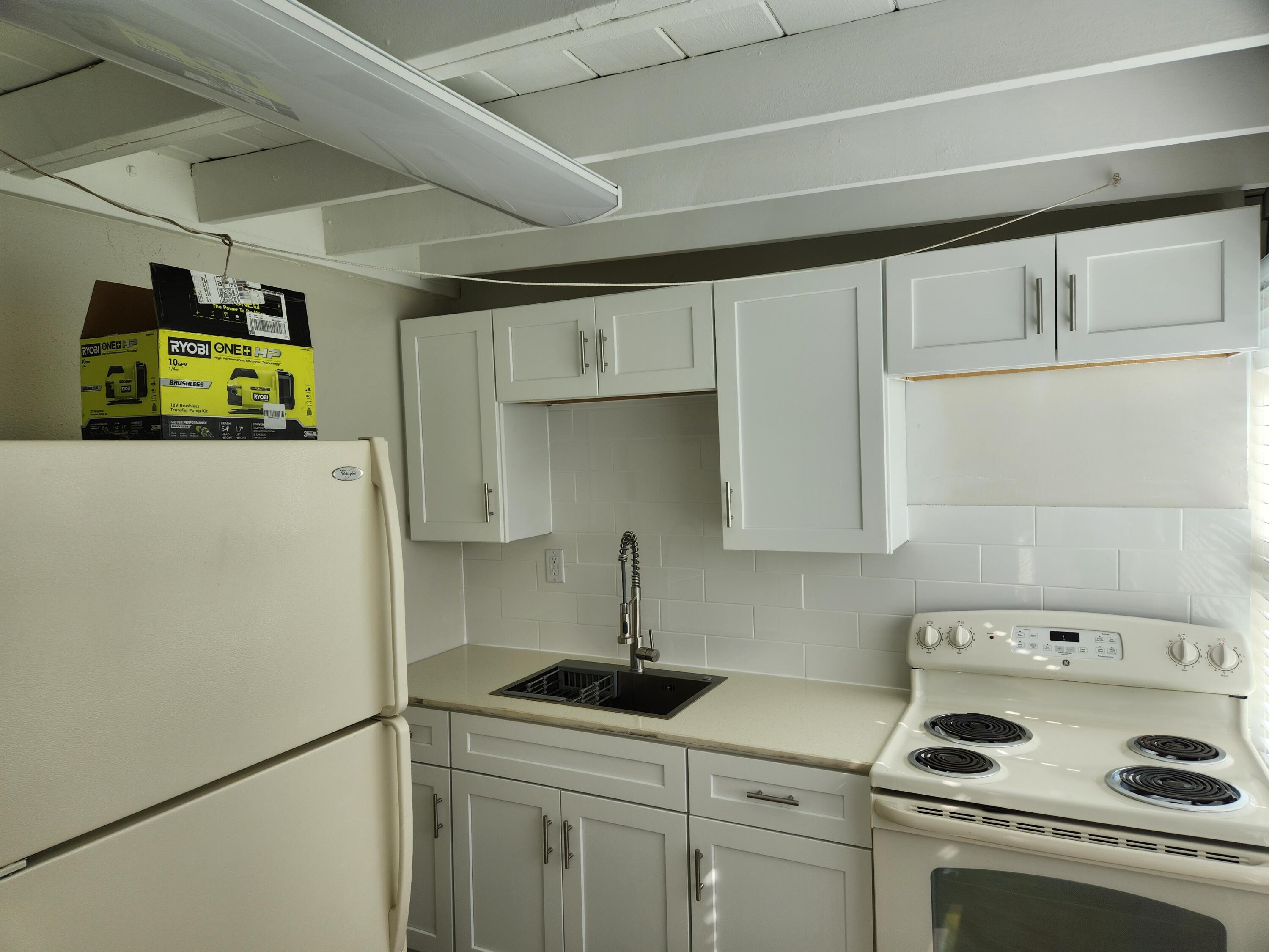 65 West 34th Street, Unit B Riviera Beach, FL 33404 - Photo 8 of 13 a kitchen with a refrigerator a stove a sink a washer and dryer
