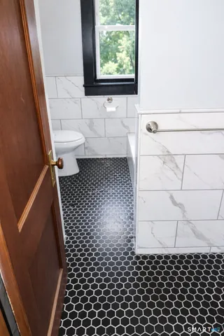 a bathroom with a toilet a window and a shower
