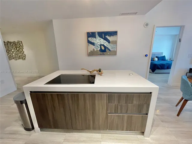 a large kitchen with kitchen island a large counter top space a sink a stove and wooden floor