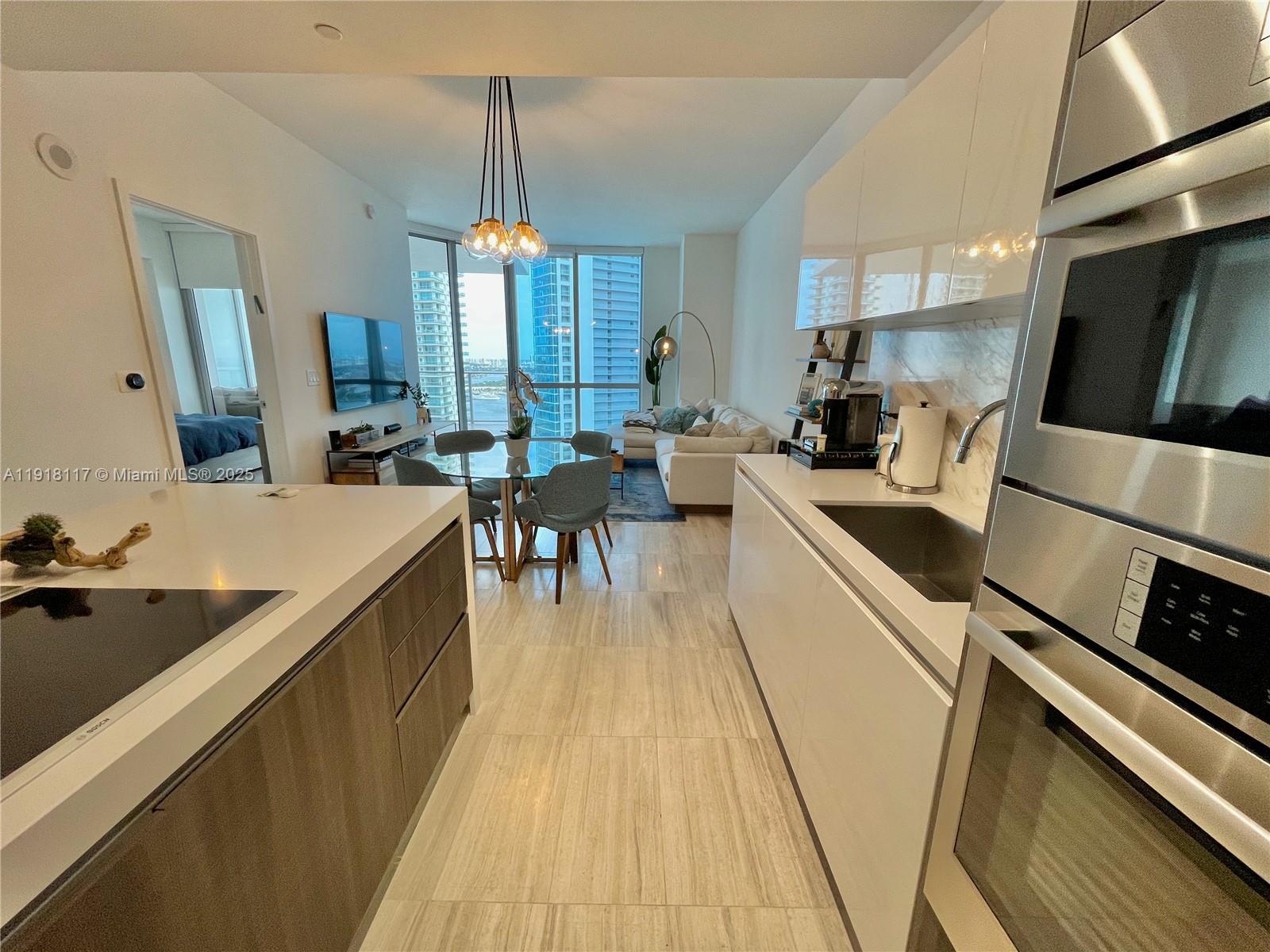 851 Northeast 1st Avenue, Unit 2605 Miami, FL 33132 - Photo 30 of 49 a large kitchen with kitchen island a large counter top space a sink a stove and wooden floor