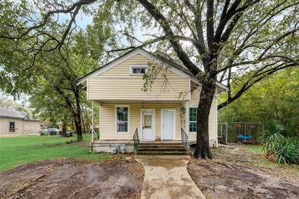 a view of a house with a yard and large tree