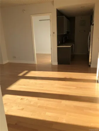 a view of kitchen and empty room with wooden floor