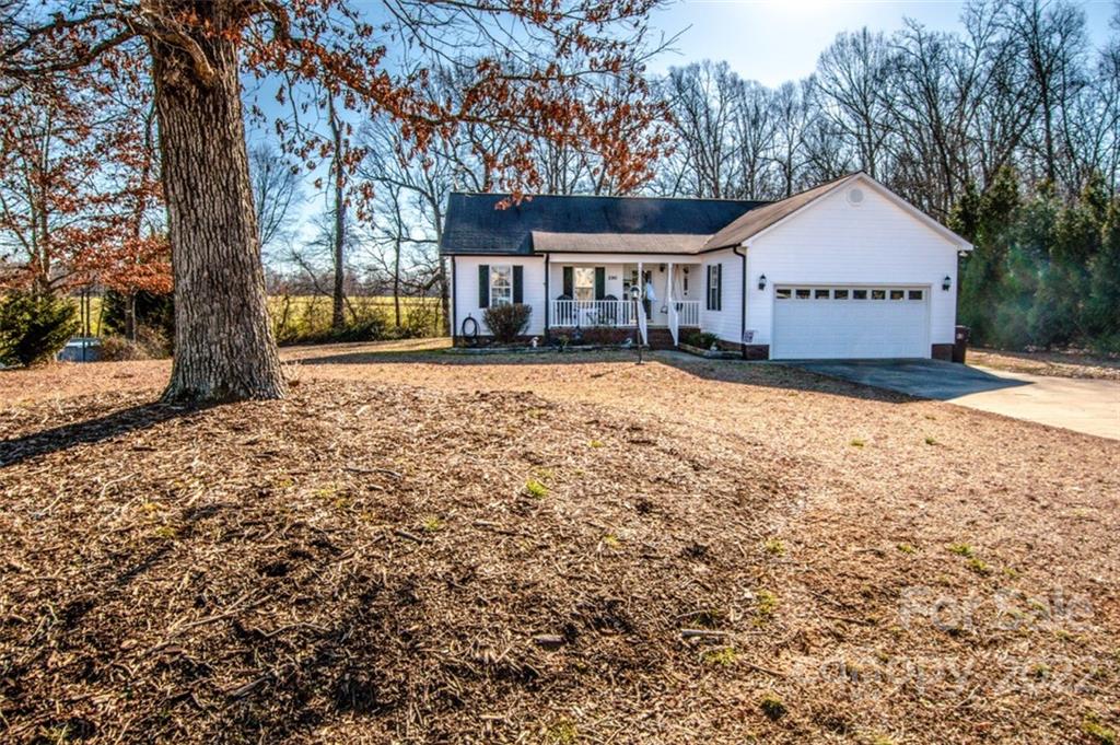 a view of a house with a yard and large tree