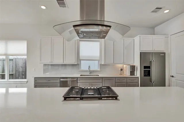 a kitchen with stainless steel appliances granite countertop a stove a refrigerator a sink and white cabinets