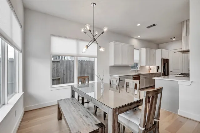 a kitchen with kitchen island a dining table chairs and white cabinets