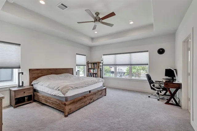 a spacious bedroom with a bed a table and a bookshelf
